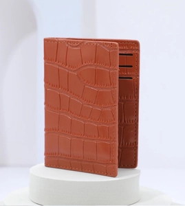 Macro detail of brown crocodile embossed leather card holder with fine stitching