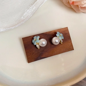 Close-up of light blue flower pearl earrings with gold plating and zircon inlay