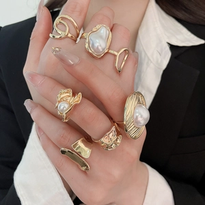 Detail of stacked gold pleated rings with baroque pearls on model's fingers