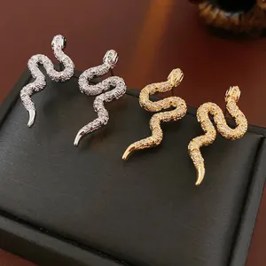 Boucles d'oreilles serpent en or et argent avec zircons sur une boîte à bijoux noire