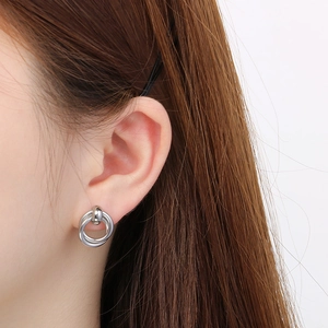 Close-up of model wearing silver interlocking double hoop earrings in polished finish