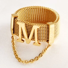 Detailed macro view of a gold mesh ring with letter M and MOM engraving details