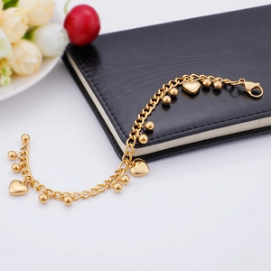Detail of gold heart charms and round beads on a stainless steel chain bracelet