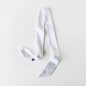 Detail eines weißen Satin-Twilly-Schals mit schwarzen Punkten und weichem Pflegeetikett
