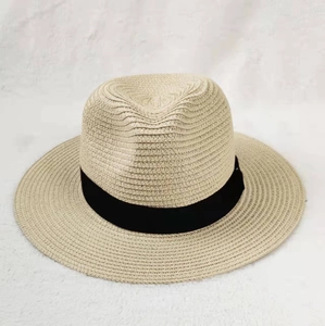 Classic wide brim straw sun hat in beige with black ribbon on white textured background