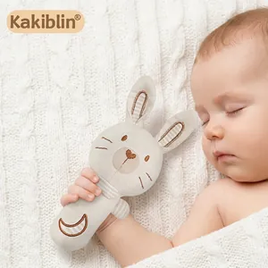 Organic cotton baby rattle bunny toy for newborns held by a sleeping infant