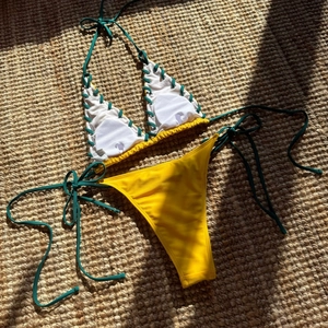 Detail of color-block bikini with lace-up eyelets and size S label on woven mat