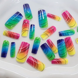 Rainbow gradient long press-on nails with black wavy lines on white ceramic tray