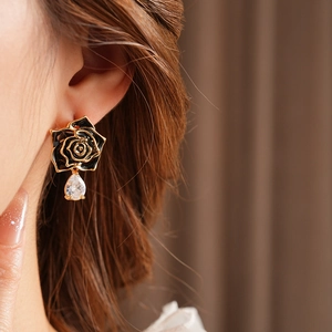 Détail de boucle d'oreille rose noire vintage avec bord doré et goutte en zircon brillant