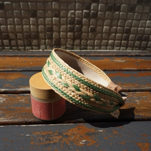 Close-up of natural raffia woven headband with green zigzag pattern and soft fabric lining