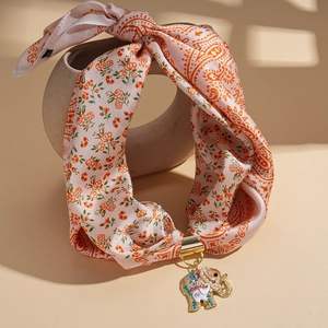 Close-up of bohemian elephant pendant with pearls and crystals on floral fabric strap