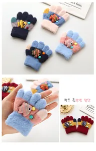 Detailed close-up of thickened knitted children gloves with 3D cartoon fish and half flannel fabric