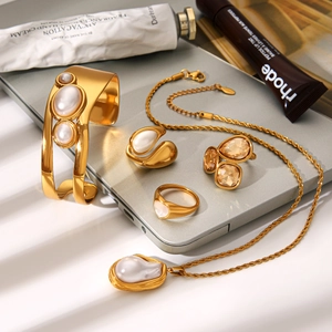 French vintage gold jewelry set with pearls and amber crystals on grey background