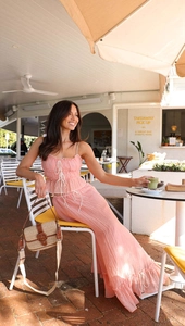 Outdoor shot of a pink pleated two-piece set with a drawstring crop top and matching skirt