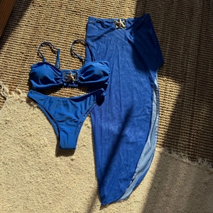 Dettaglio flat lay del bikini 3 pezzi blu reale con gonna in rete e fibbie a stella marina