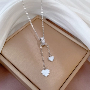 Macro detail of silver heart necklace with shell inlay and pavé stones on silk