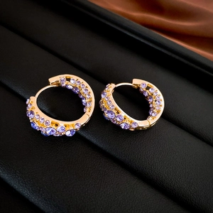 Detailed macro of gold-plated hoop earrings with pave-set purple zircon stones