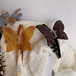 French style butterfly acetate claw clips in orange and brown on white knit fabric