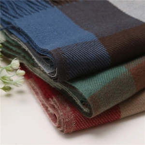 Close-up of thick plaid scarves with fringes in various colors and soft texture