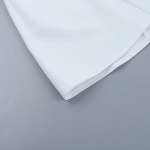 Detailed close-up of the white A-line dress hem showing refined rolled edge stitching