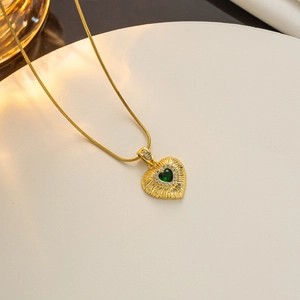 Detailed view of an 18k gold heart pendant featuring a green emerald zircon and diamonds