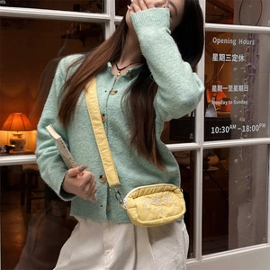 Detailed embroidery of white bows on a yellow nylon crossbody bag with silver zipper