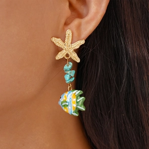 Detail of beach-style earring with starfish, blue stones, and tropical fish on a model