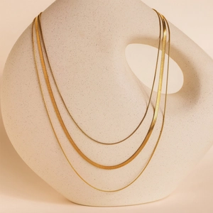 Detailed view of layered 18K gold plated stainless steel snake chains on ceramic decor