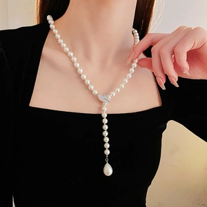 Close-up of zircon leaf charm and teardrop pearl tassel on a white pearl necklace