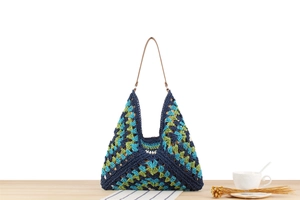 Close-up of woven paper rope bag with blue geometric pattern on a wooden table