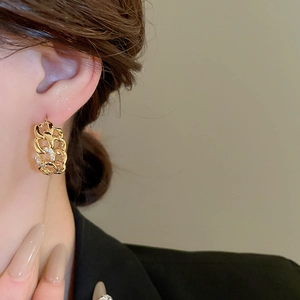 Detail of gold chain-link earring with micro-paved cubic zirconia on model ear