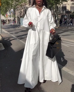 Détail d'une élégante robe chemise blanche à manches longues avec ourlet fendu pour femmes