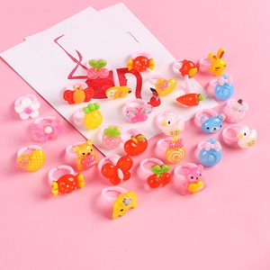 Colorful plastic rings for girls with cartoon animals and fruit shapes on pink background