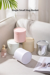 Detailed view of small cylindrical gift boxes in pink, silver, beige, and white on a sofa