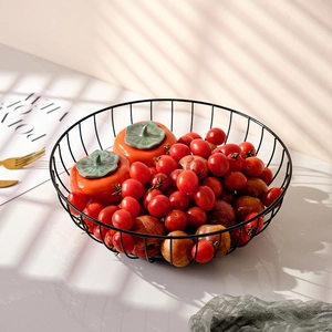 Nordic black metal wire fruit basket with fresh snacks in artistic sunlight and shadows