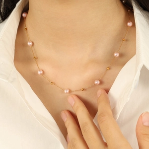 Elegant 18K gold star pearl necklace with pink pearls worn on a female model