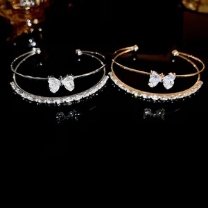 Double-layered open bangle with cubic zirconia bow and heart accents in gold and silver