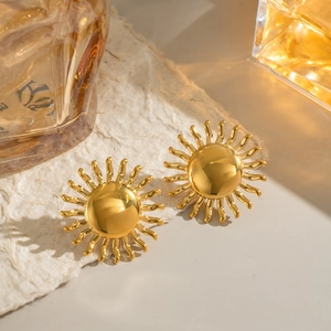 Détail macro de boucles d'oreilles soleil en or 18 carats sur tissu en lin beige