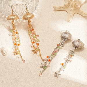 Coastal jellyfish starfish tassel earrings with colorful beads on beach sand background