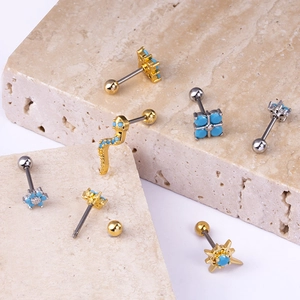 Detailed collection of gold and silver piercing studs with blue stones on marble