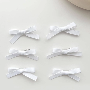 Set of six white ribbon bow hair clips arranged neatly on a clean white background