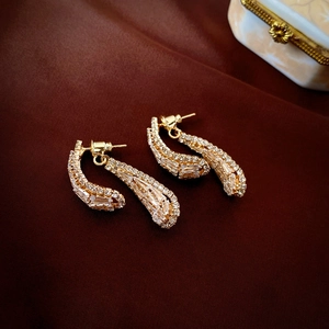 Detail of gold teardrop earrings with sparkling rectangular and round cubic zirconia