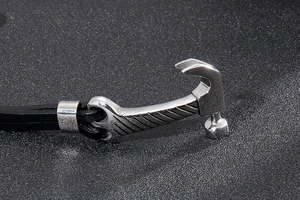 Close-up of silver hammer charm and black braided leather strap on an industrial bracelet