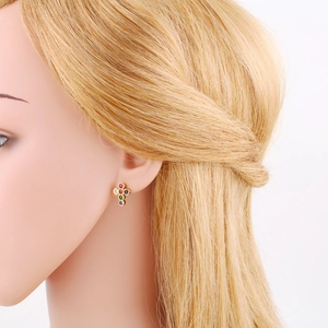 Detail view of gold cross stud earring with colorful zircon stones on a model