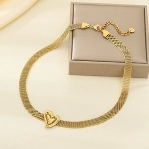 Close-up of golden mesh chain necklace featuring a central heart pendant on silk cloth