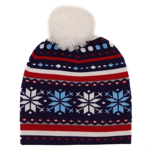Detail der Winterstrickmütze mit Schneeflockenmuster und großem weißem Kunstfell-Bommel