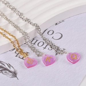 Macro view of heart-shaped glitter resin pendants with golden letters on fine metal chains