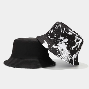 Reversible black graffiti bucket hat featuring white paint splash pattern for sun protection