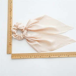 Detailed view of champagne satin hair scrunchie with long ribbons and measurement scale