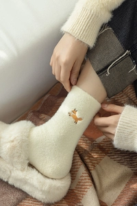 Detail of off-white plush socks with fox embroidery styled with cozy slippers